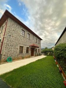 a large stone building with a grass yard next to it at Bahçeli Taş Villa in Trabzon