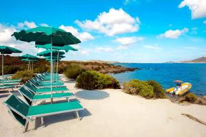 a row of chairs and umbrellas on a beach at Hotiday Golfo Aranci in Golfo Aranci
