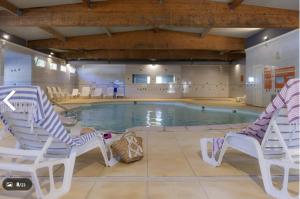 a pool with two chairs and a swimming pool at Chez Angel et Flo - E27 - Mobil home tout confort - 15 minute Europa Park - terrasse privée in Boofzheim