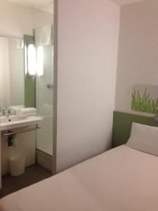 a bathroom with a bed and a sink and a shower at Ibis Budget Rambouillet in Rambouillet