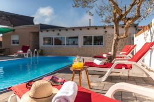 een zwembad met stoelen en een tafel met een drankje bij Villa Luma ZadarVillas in Gorica +81 foto's
