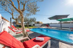 een zwembad met stoelen en een parasol naast een zwembad bij Villa Luma ZadarVillas in Gorica