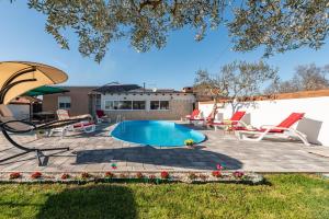 een patio met een zwembad, stoelen en een parasol bij Villa Luma ZadarVillas in Gorica