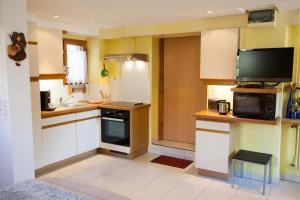 uma cozinha com armários brancos e uma televisão em Studio Rouffach em Rouffach