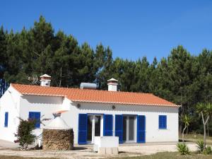 a white house with blue shutters and trees at Casa Atlântico in Odeceixe