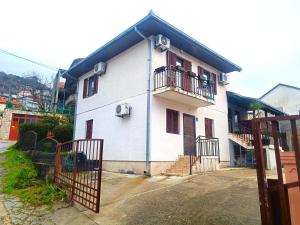 a white house with a balcony and a gate at Drenovik in Herceg-Novi