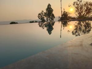 パンチガニにあるPanchgani agro tourismの夕日を背景に見えるインフィニティプール