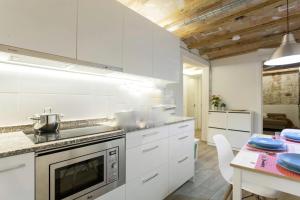 una cocina con armarios blancos y una mesa con platos azules en Barcelona Classic Palau Apartments, en Barcelona