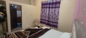 a bedroom with a bed and a purple curtain at Rajlaxmi Niketan in Ayodhya
