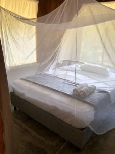a bed with white sheets and pillows in a room at Zirumake Tayrona Dentro del Parque Tayrona in El Zaino