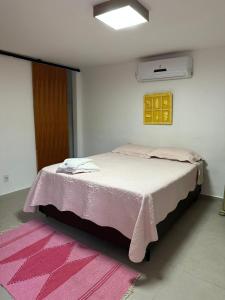 ein Schlafzimmer mit einem Bett mit einer rosa Decke in der Unterkunft Suíte Mar - Vila dos Pescadores Condomínio Portogalo in Angra dos Reis