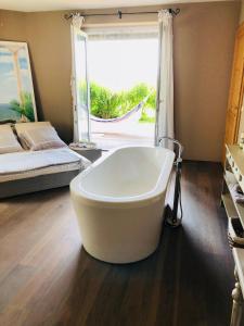 a large white bath tub in a room with a bed at Spa&Golf-Suite Velden in Velden am Wörthersee