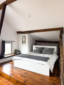a bedroom with a large white bed with wooden floors at Le Saint-Laurans in Aurignac +16 photos