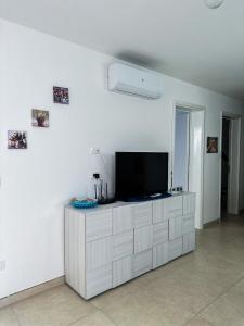 un salon avec une télévision sur un mur blanc dans l'établissement APPARTAMENTO 5 POSTI - Puglia - Marina di Pescoluse, à Marina di Pescoluse