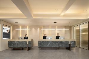three people sitting at a desk in a lobby at Atour Hotel Guangzhou Yuexiu Taojin Subway Station -Free shuttle bus to Canton Fair in Guangzhou