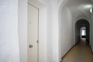 a hallway with a white wall and a door at Apartamento Diocles Centro in Mérida