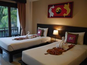 2 Betten in einem Hotelzimmer mit Schwänen darauf in der Unterkunft Ampha Place - SHA Extra Plus in Mae Nam