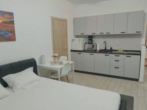 a kitchen with white cabinets and a table and a bed at Desilva Residences - Loft Club in Mamaia
