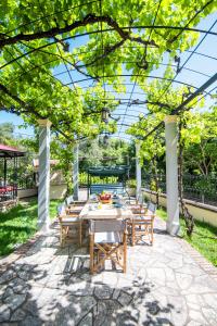 a patio with tables and chairs under a pergola at Le Chateau by CorfuΕscapes in Corfu