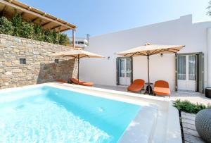 a pool with orange chairs and umbrellas next to a house at Simple House Mykonos Sunset in Mikonos