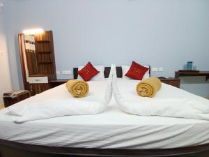 a bed with white sheets and yellow and red pillows at Veera Residency Gingee in Gingee