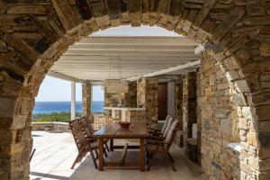 an archway in a stone house with a table and chairs at Villa Marble Tinos in Agios Fokas