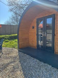 a small building with a door and a bench at Springfield oaks Glamping Pod in Isle of Wight +3 photos