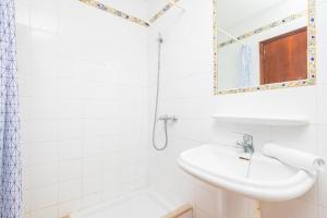 a white bathroom with a sink and a mirror at La Ceiba in Santanyi