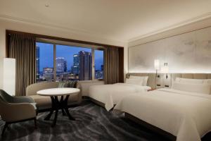 a hotel room with two beds and a table and a window at The Westin Osaka in Osaka