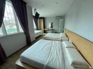 two beds in a room with two windows at Tropical villa in Kuantan