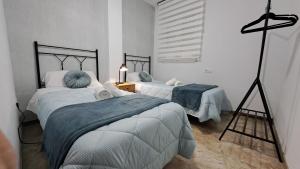 ein Schlafzimmer mit 2 Betten und einer Lampe in der Unterkunft Apartamentos Maria Cristina con parking gratis in Córdoba