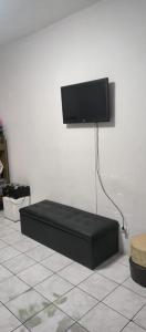 a black bed in a room with a tv on a wall at Cantinho do Forte in Praia Grande