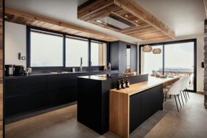 una cocina con armarios negros y una encimera con mesa en Chalet 1786 - OVO Network, en Notre-Dame-de-Bellecombe