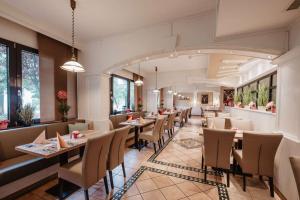 a restaurant with tables and chairs in a room at Kurhotel Unter den Linden in Bad Füssing