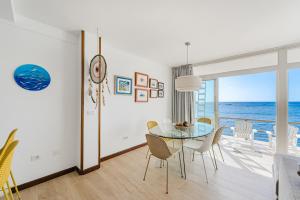 una sala da pranzo con tavolo in vetro e vista sull'oceano di Symphony Medano by Welcome Tenerife a El Médano Altre 24 foto