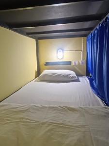 1 dormitorio con 1 cama con cortina azul en 3Plus1 Hostel Patong, en Patong Beach