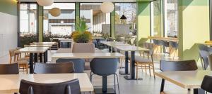 a restaurant with tables and chairs and windows at B&B HOTEL Famalicão in Vila Nova de Famalicão