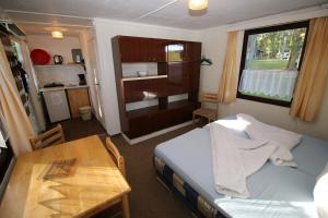 a small room with a bed and a table and a window at Bungalow WALD & SAND direkt am Strand in Dranske