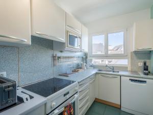 una cucina bianca con mobili bianchi e un lavello di La Trinité-sur-Mer : Appartement 3 pièces avec parking, proche port et plages - FR-1-477-180 a La Trinité-sur-Mer
