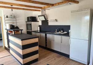 a kitchen with a white refrigerator and a black counter at La maison du vieux bourg in Perrier