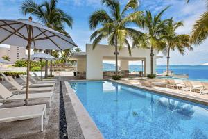 a swimming pool with chairs and umbrellas next to the ocean at Harbor 171 TN 2110 in Puerto Vallarta