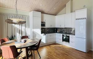 a kitchen with white cabinets and a table with chairs at 3 Bedroom Cozy Home In Grebbestad in Grebbestad