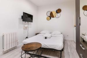 a bedroom with a bed and a table and a tv at Studio fonctionnel hopital bichat - paris 18 - 2P in Paris