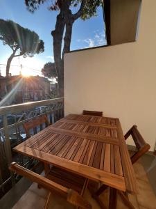 a wooden table on a balcony with a tree at Villetta Onda Blu in Punta Marina