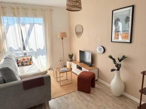 ein Wohnzimmer mit Sofa und Fernseher in der Unterkunft Appartement Cosy avec Balcon in Parentis-en-Born
