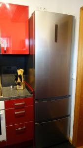 a stainless steel refrigerator in a kitchen with red cabinets at Fischerhaus am See in Berlin