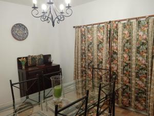 a dining room with a glass table and a floral curtain at Albufeira INN - Mulatinho V3 in Olhos de Água