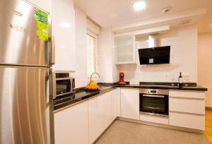 cocina con armarios blancos y nevera de acero inoxidable en Apartamentos Amaiur, en Estella