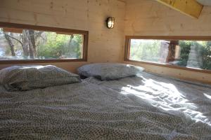 una camera da letto con un letto in una cabina di legno di La cabane des bords d'Ariège a Grépiac