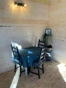 un tavolo con sedie in una stanza con una parete in legno di La cabane des bords d'Ariège a Grépiac